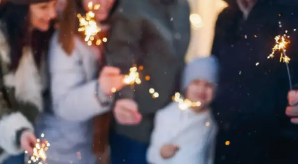 Rodzina z dziećmi świętuje Sylwestra, trzymając zimne ognie. Idealne miejsce, gdzie na sylwestra z dziećmi, by stworzyć magiczne wspomnienia.