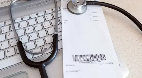 Stetoskop na klawiaturze laptopa obok recepty lekarskiej.