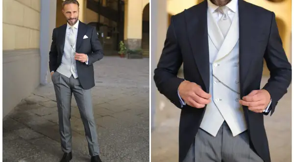 Uomo elegante in spezzato con cravatta, gilet e catenella da orologio.