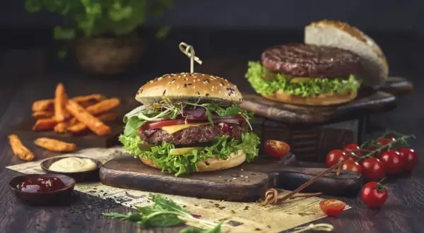 Pyszny hamburger, którego skąd pochodzi, z soczystą wołowiną, warzywami i serem, podany z frytkami i sosami.
