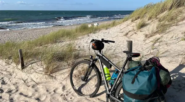 Rower z sakwami na piaszczystej plaży, gotowy na przygodę. Trasa rowerowa nad morzem czeka!