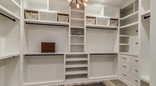 Armario de pladur blanco con cestas, caja de Louis Vuitton y barras para colgar ropa.