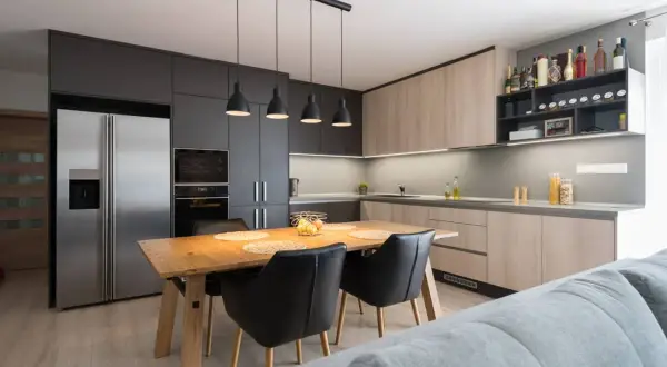 Moderna cocina abierta con isla de comedor, electrodomésticos integrados y estanterías para vinos.