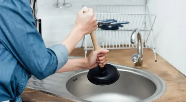 Persona usa uno sturalavandini per risolvere il problema di come sturare il lavandino della cucina.