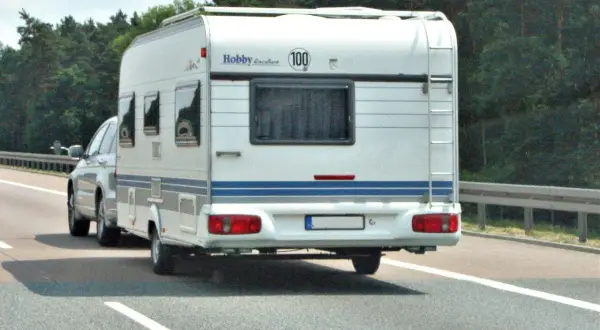 Samochód ciągnie przyczepę kempingową Hobby Excellent. Kierowca z kodem 96 prawo jazdy cieszy się podróżą.