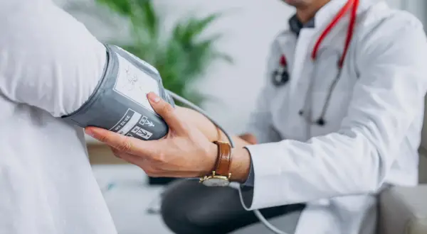 Lekarz mierzy ciśnienie pacjentowi, co jest kluczowe w diagnostyce i leczeniu, jak obniżyć wysokie ciśnienie rozkurczowe.