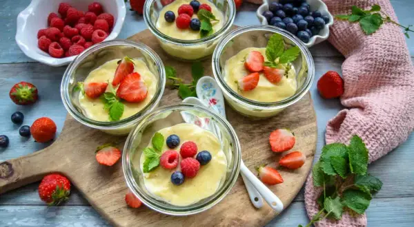 Vier Gläser mit selbstgemachtem Pudding, garniert mit frischen Beeren und Minze. Ein Genuss für Augen und Gaumen!