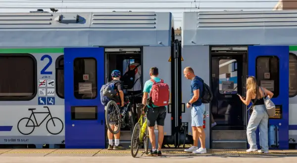 Ludzie z rowerami wsiadają do pociągu, szukając tanich biletów Intercity na wakacyjną podróż.