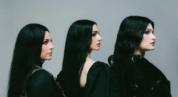 Drei Frauen mit langen schwarzen Haaren und dunklem Make-up, die wie eine Metal-Band posieren.
