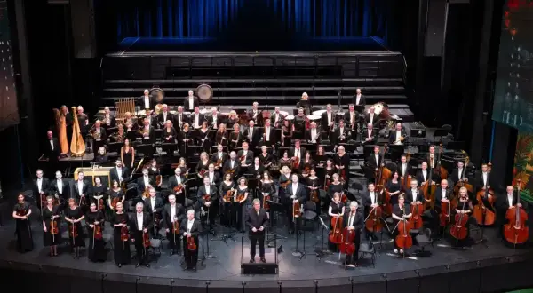 Wielka orkiestra symfoniczna na scenie, muzycy w strojach galowych, dyrygent. To właśnie opera co to za widowisko!