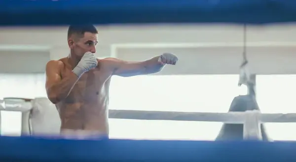 A boxer throws punches in a ring, practicing his moves. This is how shadow boxing, a training technique, likely began.