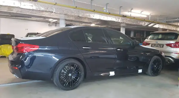 Ciemnogranatowe BMW 520d xDrive z czarnymi felgami stoi w garażu.