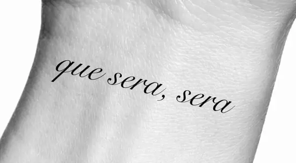 Tatuaż na nadgarstku z napisem "que sera, sera", co oznacza "co ma być, będzie".