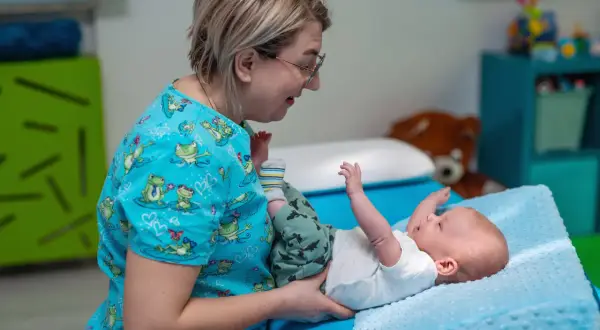 Terapeuta pomaga dziecku z problemem refluksu ukrytego, wykonując delikatne ćwiczenia.