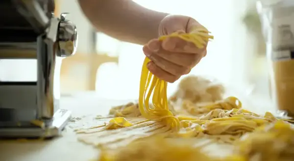 Ręce formują świeży makaron z maszyny. Idealny przepis na domowy makaron, który zachwyci każdego.