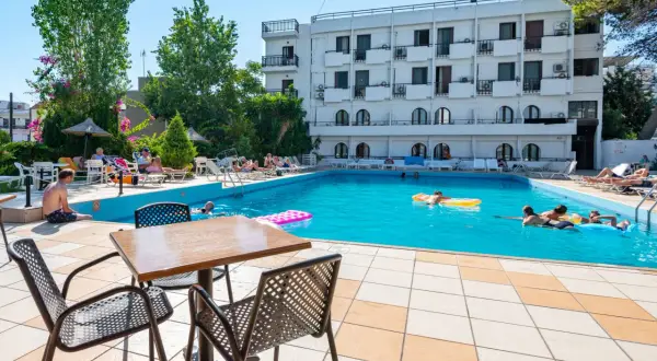 Basen hotelowy, ludzie relaksują się na leżakach i pływają. Wiele pozytywnych heronissos hotel opinie potwierdza ten widok.