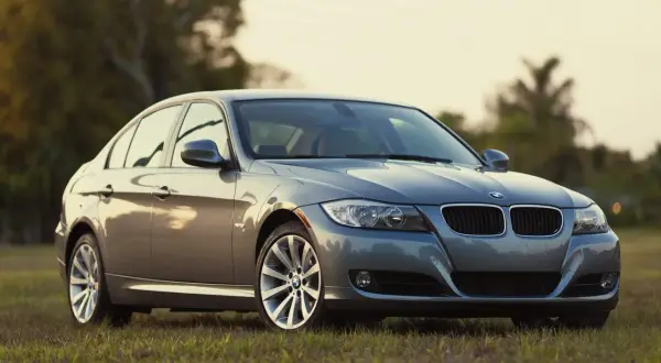 Szary sedan BMW na trawie. Klasyczne rodzaje karoserii, jak ten, są ponadczasowe.