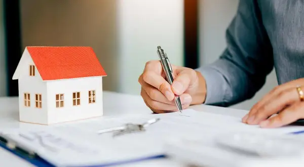 Firma contratto immobiliare: attenzione ai rischi nel vendere casa con agenzia. Modello casa, chiavi e firma su documento.