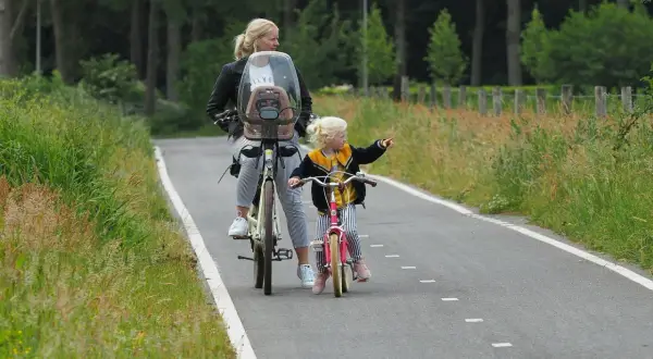 Mama i córka na rowerach odkrywają rodzinne trasy rowerowe. Dziecko wskazuje drogę.