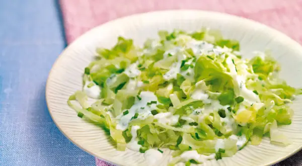 Frischer Spitzkohlsalat mit cremigem Dressing und Schnittlauch auf einem Teller.