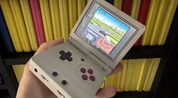Gra wyścigowa na ekranie konsoli Game Boy Color, trzymanej w dłoni.