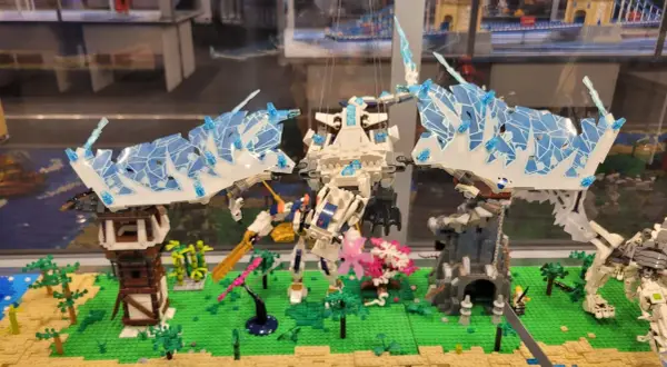 Lodowy smok w muzeum LEGO w Warszawie walczy z robotem na tle miniaturowej wioski.