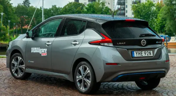 Grå Nissan Leaf med texten "ViBilägare TESTAR" på sidan. Bilen står vid en kaj, kanske med ett nissan leaf problem att undersöka.