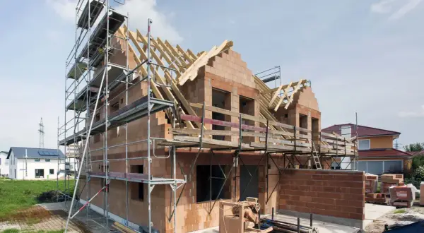 Rohbau firma im Einsatz: Ein Haus im Bau mit Gerüst, Ziegelwänden und Dachstuhl.