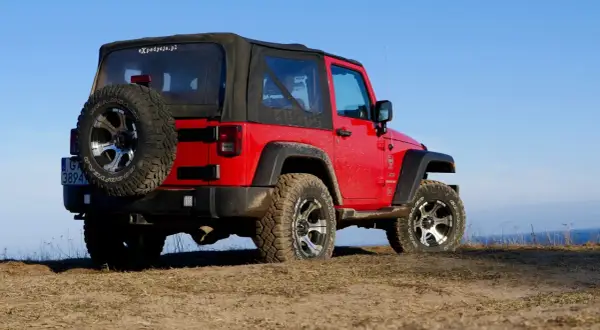 Czerwony Jeep Wrangler, gotowy na każdą wyprawę, niczym przekraczający Rubikon.