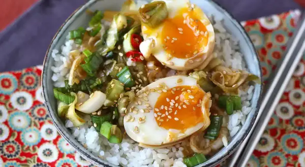 Skål med ris, halverade mayak gyeran-ägg, salladslök och sesamfrön.