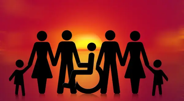 Famiglia unita al tramonto, con un membro su sedia a rotelle. Speranza per una pensione invalidità 800 euro.