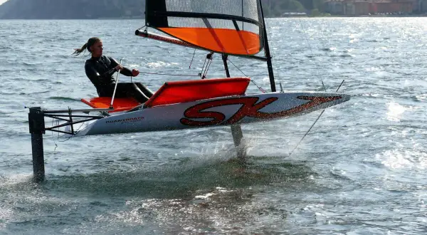 Vela da regata con foil che solleva lo scafo dall'acqua, creando un effetto simile a una falena in volo.