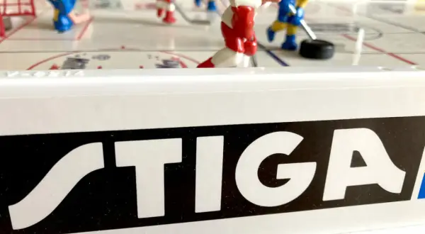 Stig Hjelmquist spelar hockey på STIGA-bordet. Röda och blå spelare kämpar om pucken på isen.