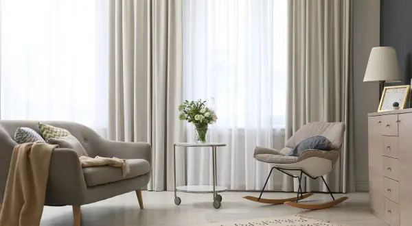 Elegantes tipos de cortinas para ventanas, con un sofá y mecedora en un salón moderno.