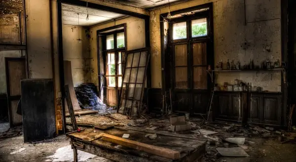 Intérieur d'un lieu abandonné en France. Un vieux bureau en bois trône au milieu des débris, sous des ampoules nues.