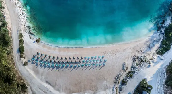 Rajska plaża na Thassos z turkusową wodą i rzędami leżaków. Idealne miejsce na relaks i podziwianie pięknych widoków.