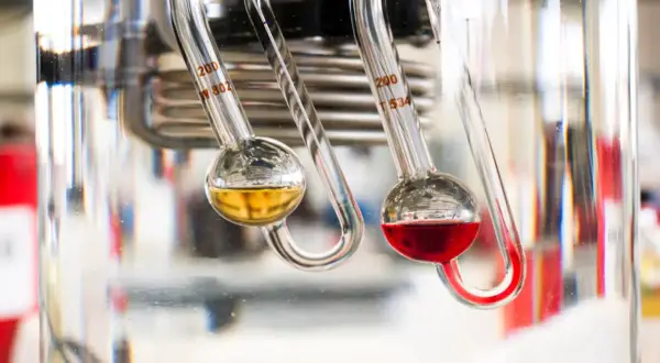 Due viscosimetri misurano la viscosità di oli motore diversi. Uno giallo, uno rosso.