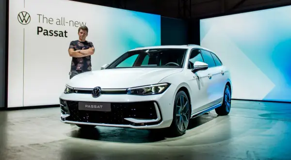 Mężczyzna stoi obok białego kombi, prezentując nowy model Passat B9.