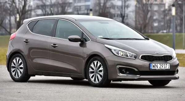 Brązowy Kia Ceed 1.6 benzyna z polskimi tablicami rejestracyjnymi WN 2937J zaparkowany na zewnątrz.