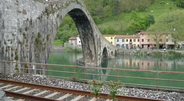 Ponte del Diavolo a Borgo a Mozzano, con case colorate e un fiume verde.