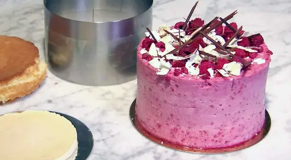 En vacker hallontårta med chokladdekorationer och grädde. Perfekt tårta inspo för nästa bakprojekt!