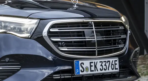 Dettaglio anteriore di un'auto di lusso con griglia cromata e fari a LED. La cromatura esterni risalta sulla carrozzeria scura.
