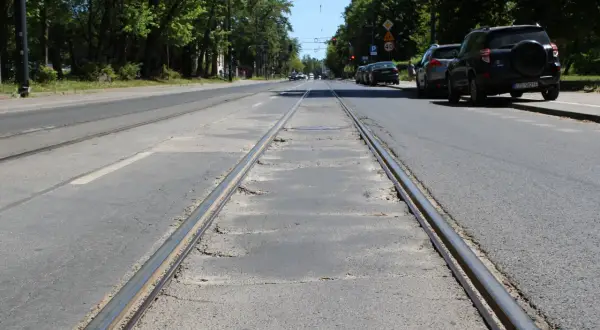 Torowisko tramwajowe na ulicy w Łodzi. Samochody stojące na poboczu sugerują utrudnienia w ruchu.