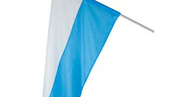 Biało-niebieskie flagi kościelne na maszcie, gotowe do procesji lub uroczystości.