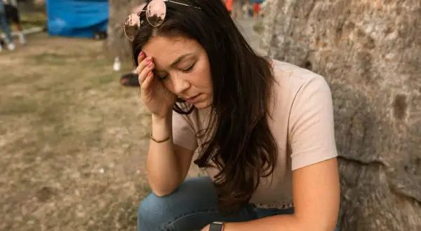 Vrouw met zonnebril op haar hoofd, hand op haar voorhoofd, lijkt te lijden aan een fobie voor naalden.
