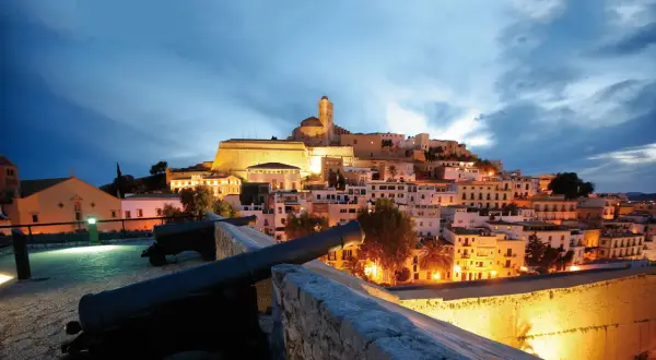 Alte Kanonen blicken auf die beleuchtete Altstadt von Ibiza im Winter.