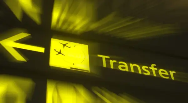 Żółty znak lotniskowy z ikoną samolotu i napisem "Transfer". Czy można opuścić lotnisko podczas przesiadki?