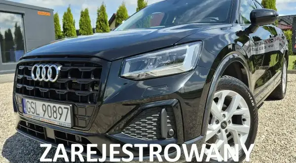Czarny Audi Q2 na żwirowym podjeździe. Sprawdź atrakcyjną audi q2 cena i zarezerwuj jazdę próbną.