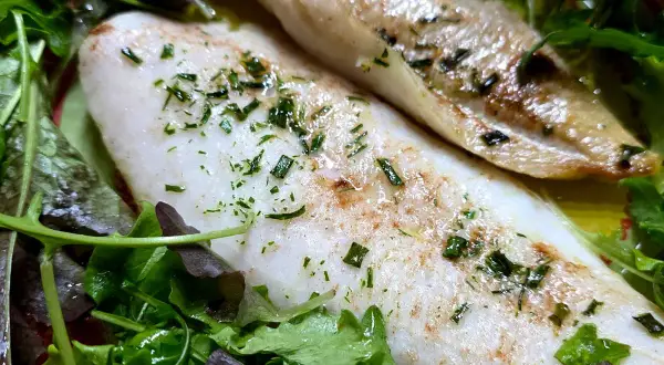 Delizioso merluzzo in friggitrice ad aria, cotto alla perfezione e servito su un letto di insalata fresca.
