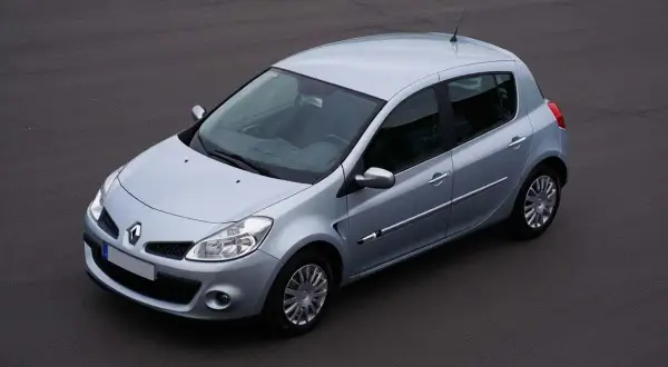 Vue aérienne d'une Renault Clio 3 argentée, modèle à injection, garée sur un sol asphalté.